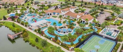 Vista aérea de una zona residencial con una gran piscina, canchas de tenis y un muelle.