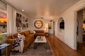 Ein Wohnzimmer mit braunem Sofa, einem Couchtisch und einem Fernseher auf einem Schrank.