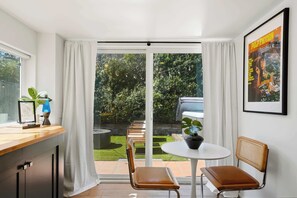 Eine moderne Küche mit Essbereich, einer Schiebetür zu einem Garten und einem gerahmten Poster an der Wand.