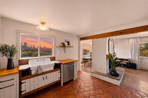 A modern kitchen with a city view, a wooden countertop, and a tiled floor. - Golden Hill 7BR Retreat with Private Hot Tub (San Diego)