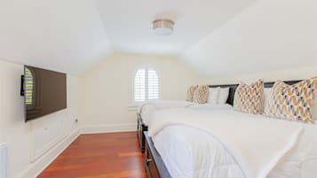 Ein Schlafzimmer mit einem großen Bett, einem an der Wand montierten Fernseher und einem Fenster mit Rollläden.