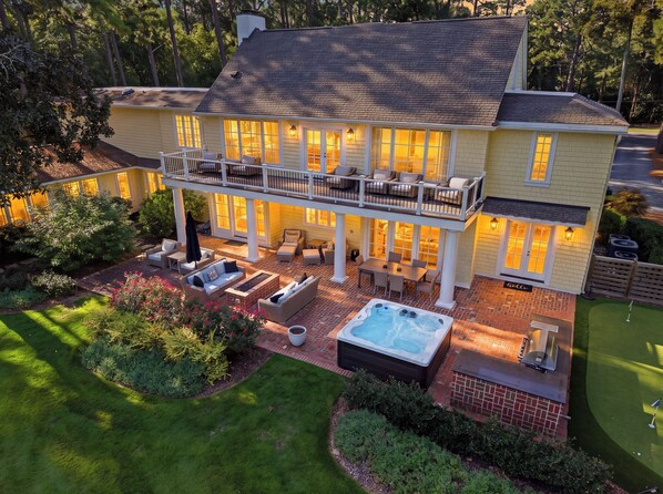 A two-story house with a balcony, outdoor seating, and a hot tub.