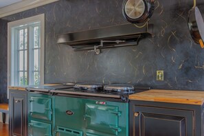 A kitchen with a stove, a range hood, and a window.