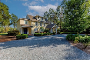 A two-story house with a gravel driveway and a well-maintained garden.