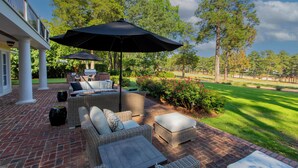 A patio with wicker furniture, a grill, and a view of a golf course.