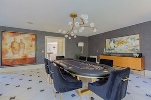 A modern conference room with a round table, black chairs, a chandelier, and artwork on the walls.