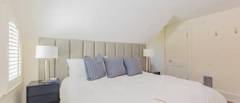 Une chambre à coucher bien rangée, avec un lit, deux tables de chevet et une tête de lit.