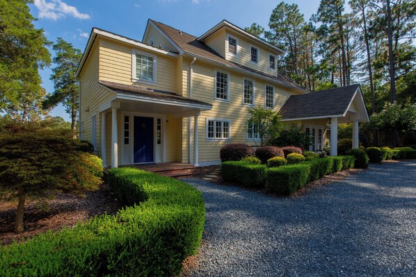 A two-story house with a front porch, a driveway, and a well-maintained garden.