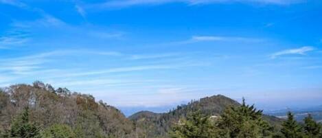 A balcony with a view of a forested mountain range under a clear sky.