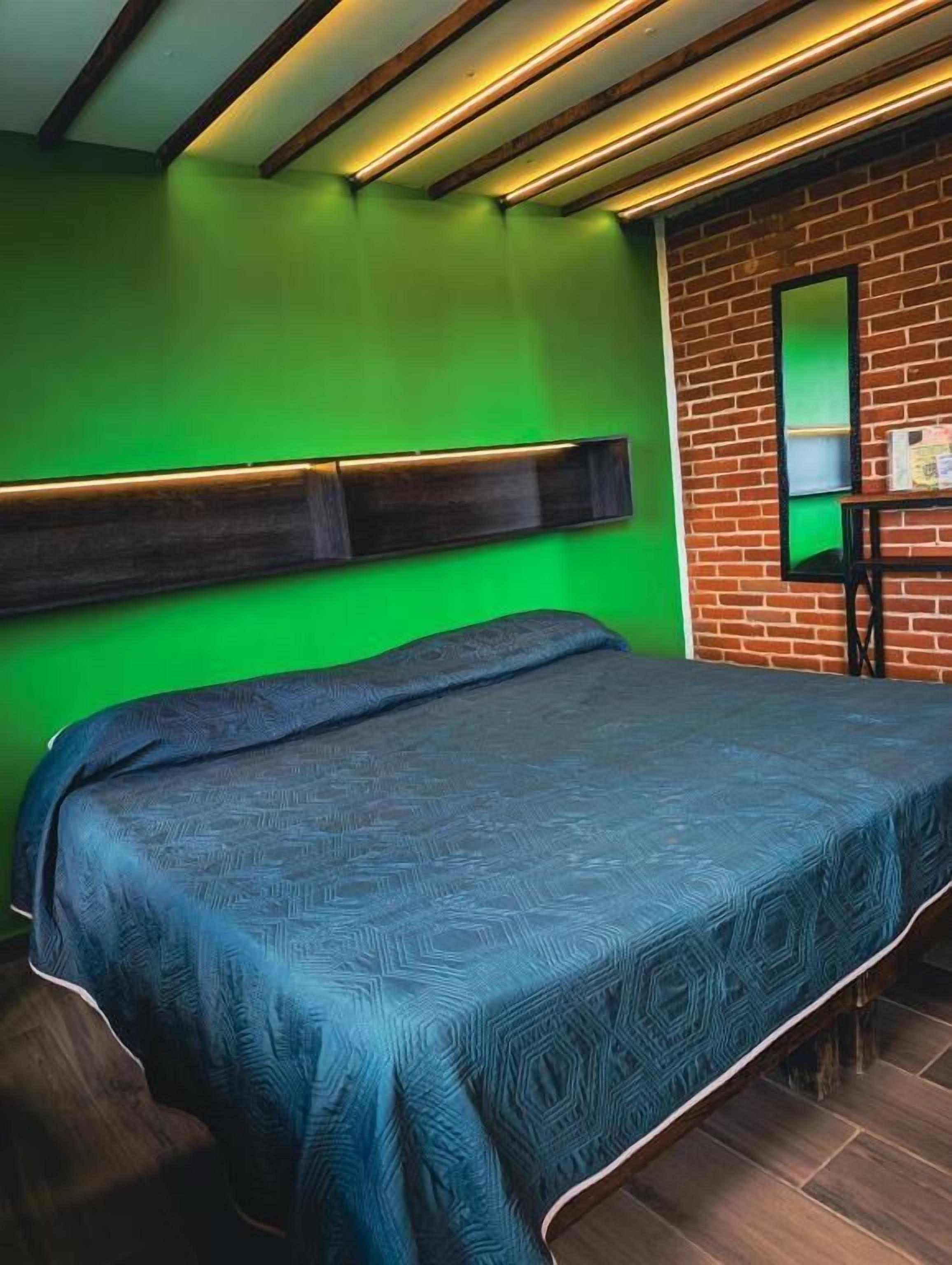 Una habitación con una cama, una pared de ladrillo y una pared verde.
