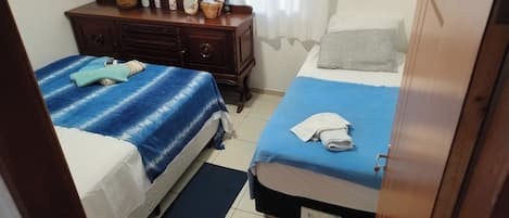 Una habitación con dos camas, un aparador de madera y una ventana con cortinas.