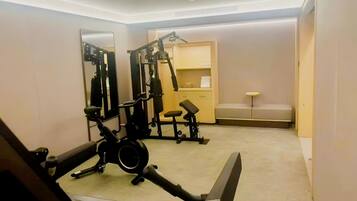 Un gimnasio con equipo de ejercicio, un espejo, una banca y una pequeña zona de estar.