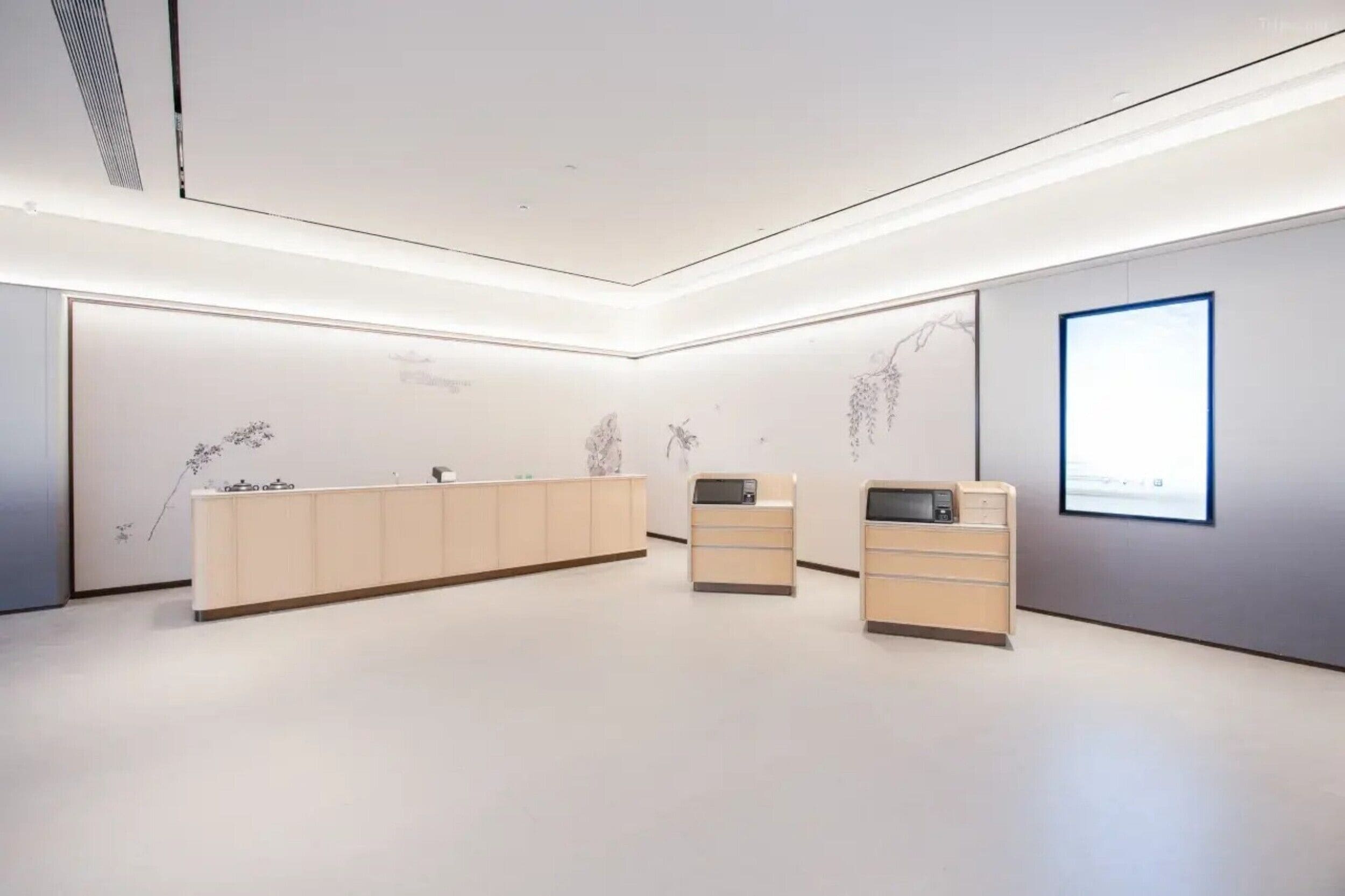 Un área de recepción moderna y minimalista, con una larga barra de mostrador y dos puestos más pequeños.