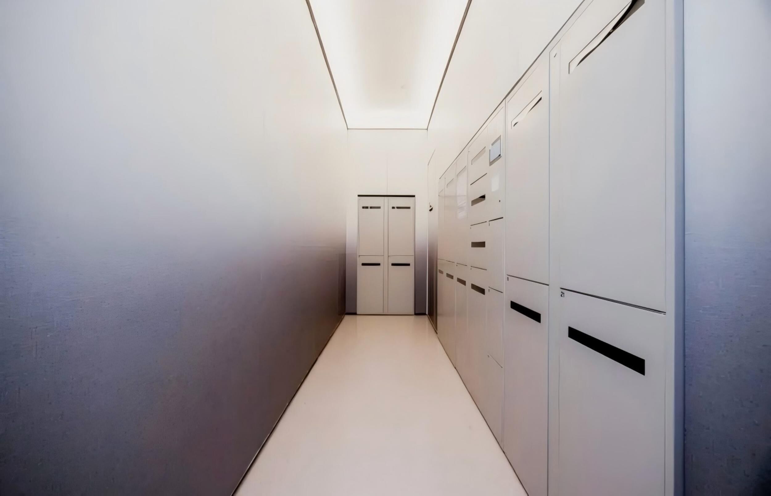 A hallway with lockers on one side and a door at the end.
