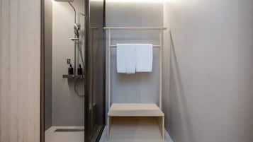 Un baño moderno con cabina de ducha de vidrio, un perchero con una toalla blanca y un estante pequeño.
