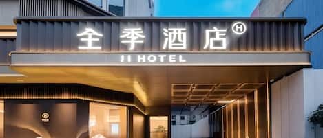 A hotel entrance with a modern design, featuring a prominent sign with Chinese characters and the word 'HOTEL' underneath.
