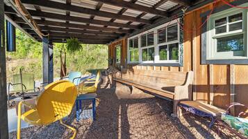 A covered outdoor seating area with a bench, chairs, and a table.
