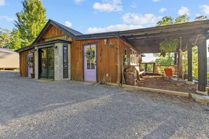 Ein Holzhaus mit überdachter Veranda, einem Schotterweg und einem Holzzaun.