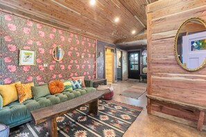 Ein gemütliches Wohnzimmer mit einem grünen Sofa, einem Holztisch und gemusterten Teppichen.