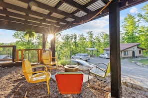 An outdoor seating area with chairs and a fire pit, overlooking a parking area and a building with a distinctive pattern. - Meadowlark: Adventure Bunkhouse Near Downtown (Chattanooga)