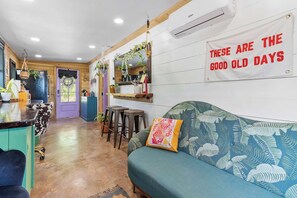 A cozy interior with a sofa, a bar area, and a wall with a motivational quote. - Meadowlark: Adventure Bunkhouse Near Downtown (Chattanooga)