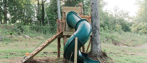 A playground with a slide and a wooden structure.