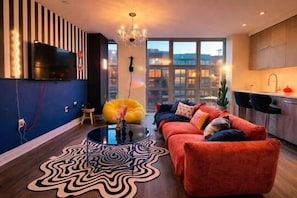 A modern living room with a sofa, a coffee table, and a TV mounted on the wall.