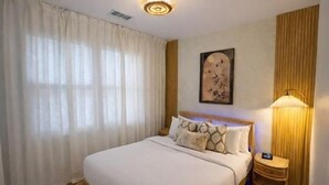 Quarto de hotel com uma cama grande, uma mesa de cabeceira, uma luminária e um quadro na parede.