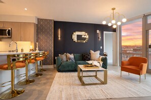 A modern living room with a green sofa, a coffee table, and a bar area with stools.