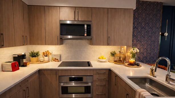 Une cuisine moderne avec des meubles en bois, des appareils électroménagers en acier inoxydable et un papier peint à motifs.