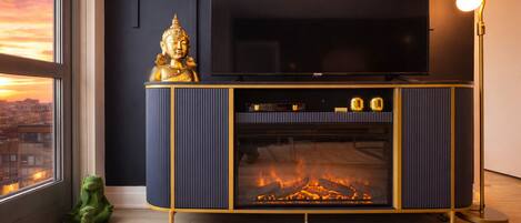 A modern living room with a fireplace, a television mounted on the wall, and a decorative Buddha statue on a cabinet.