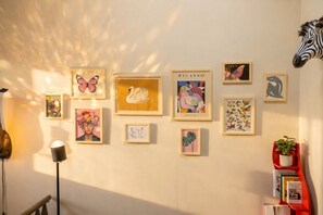 A wall with various framed artworks, including a swan, a butterfly, and a zebra head.