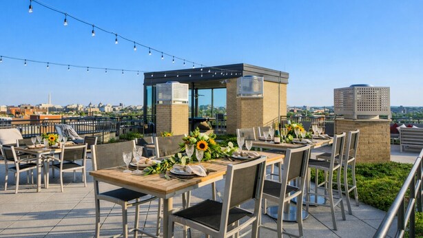 Un espacio de comedor al aire libre con mesas dispuestas para dos, equipado con sillas y diferentes tipos de vajilla.