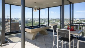 Een pooltafel en stoelen op een balkon met uitzicht op de stad.