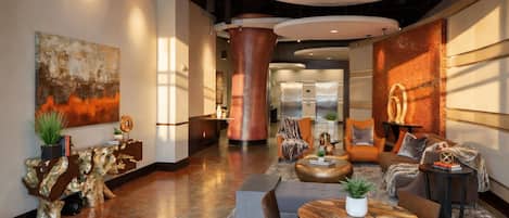 A modern lobby with a central seating area, a large abstract painting, and a reception desk.