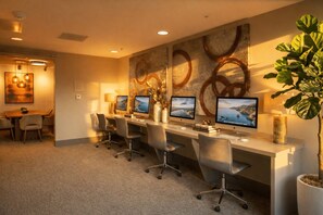 A conference room with a long table, four chairs, and three desktop computers.