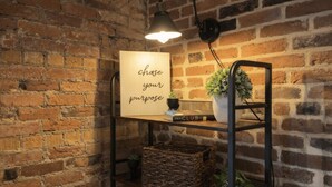 Een bakstenen muur met een plank waarop een bord, een boek en een plant staan.