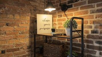 A brick wall with a shelf holding a sign, a book, and a plant.
