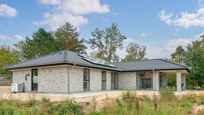 A modern two-story house with a brick exterior, large windows, and a covered porch. - Gorgeous home in Gilleleje with sauna (Gilleleje)