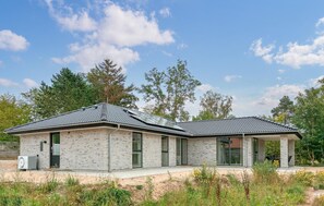 Ein modernes, zweistöckiges Haus mit Ziegelaußenwand, großen Fenstern und einer überdachten Veranda.