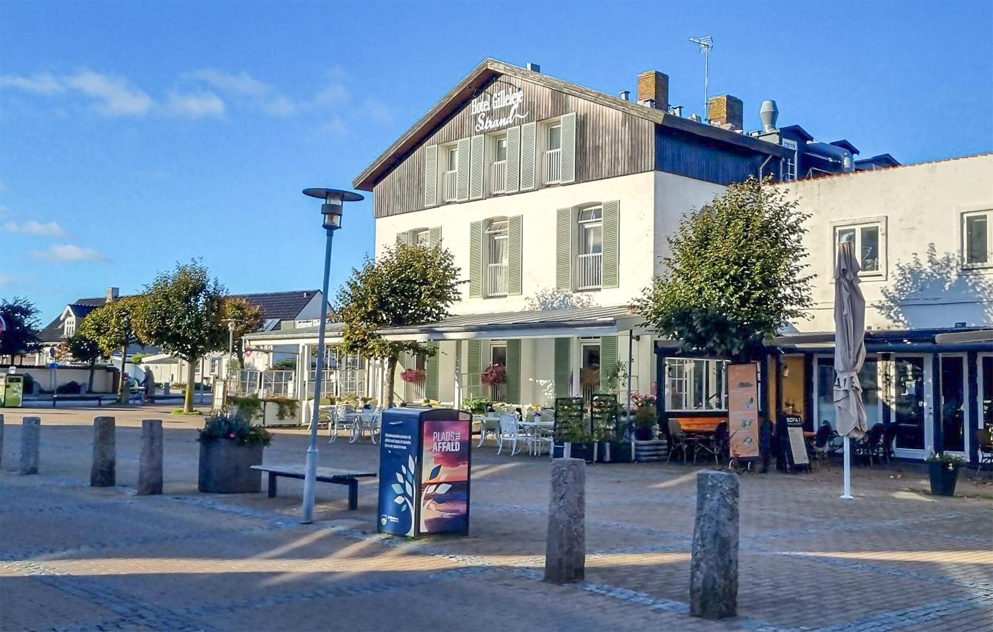 A hotel with a terrace, outdoor seating, and a signboard.