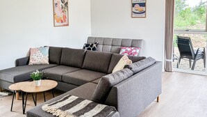 A modern living room with a grey sectional sofa, a round wooden coffee table, and a striped throw blanket. - Gorgeous home in Gilleleje with sauna (Gilleleje)