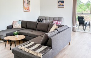 Ein modernes Wohnzimmer mit einem grauen Modulsofa, einem runden Couchtisch aus Holz und einer gestreiften Decke.