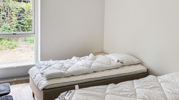 A bedroom with a bed, a window, and a view of greenery outside. - Gorgeous home in Gilleleje with sauna (Gilleleje)