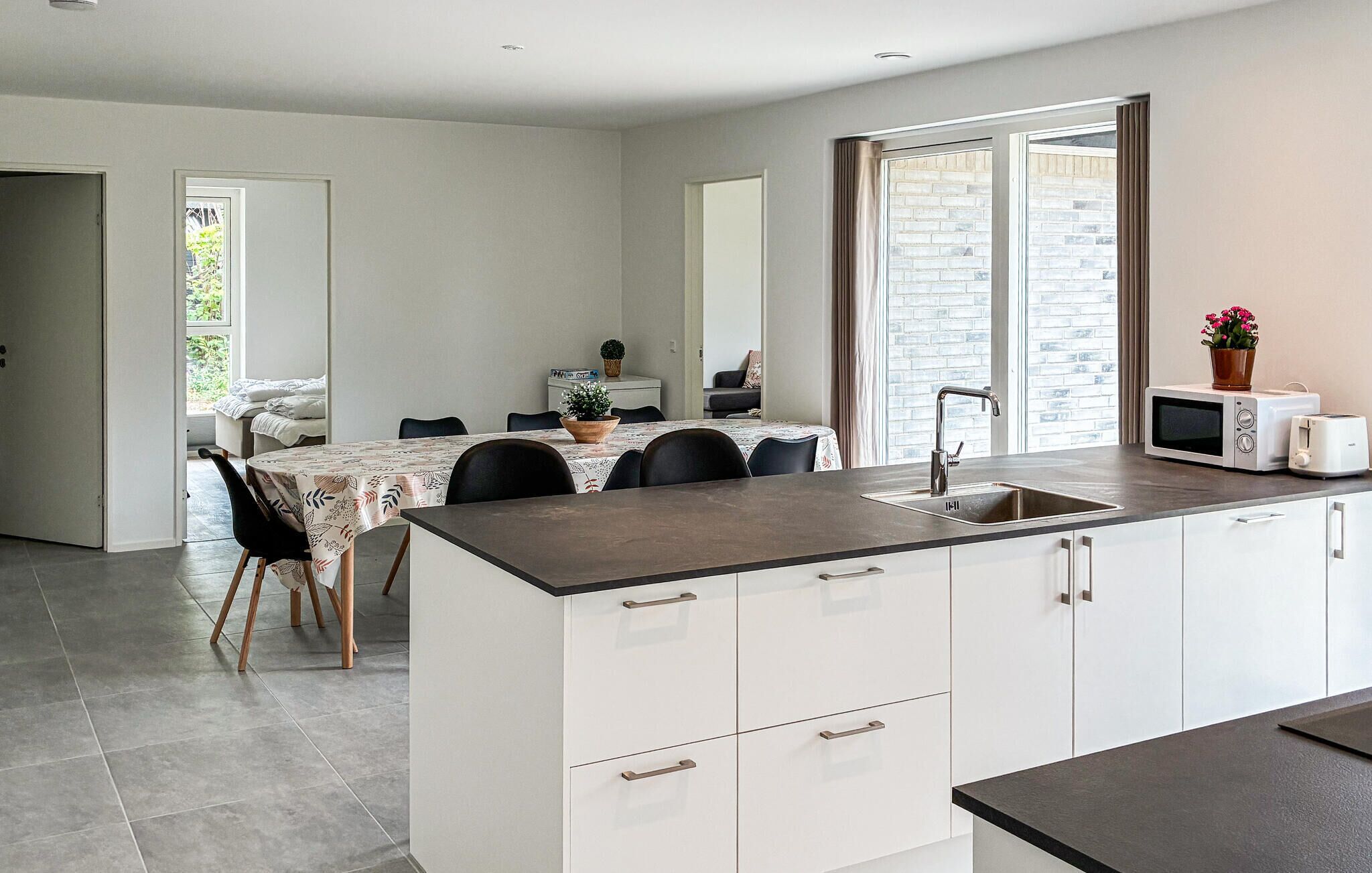 Une cuisine moderne dotée d’un îlot central, de meubles blancs et d’un coin repas avec une table et des chaises.