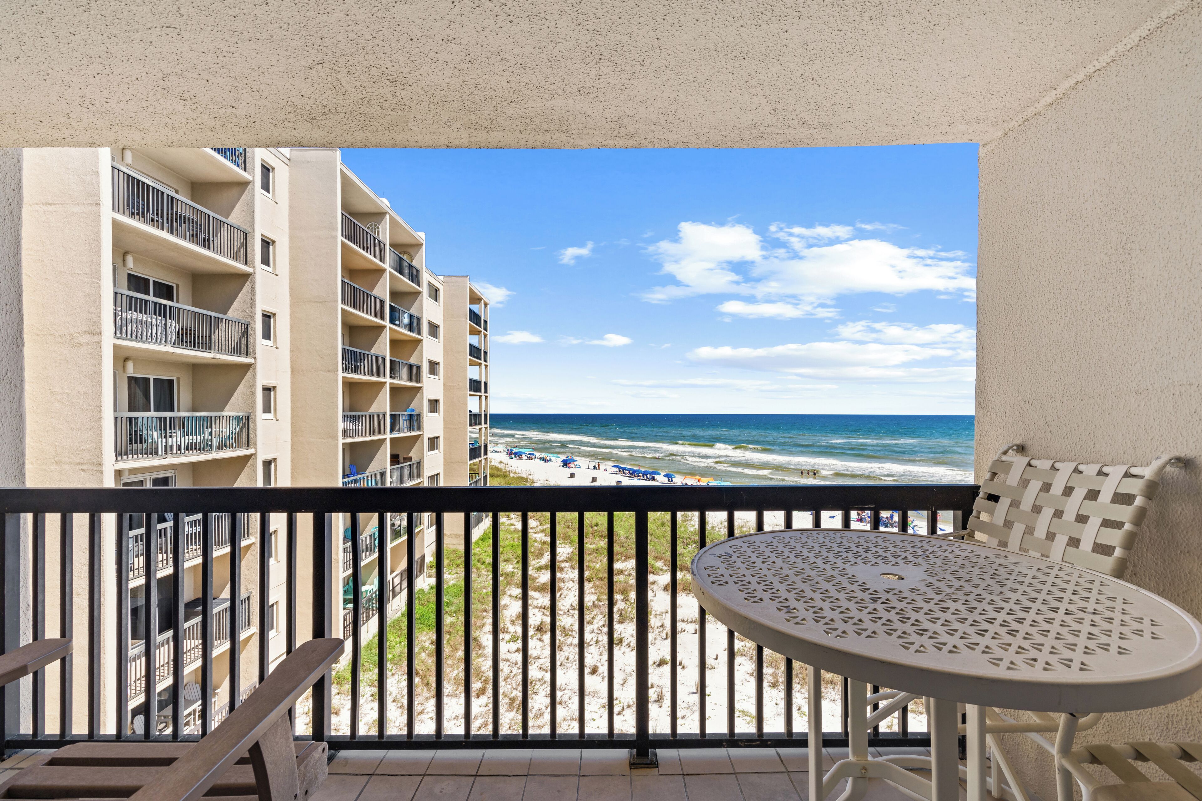Ein Balkon mit Blick auf Strand und Meer, ein runder Tisch und ein Stuhl.