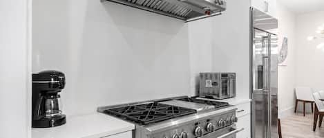 Una cocina moderna con estufa a gas, horno, cafetera y microondas integrado.