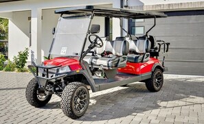 A red and gray golf cart parked on a paved surface.