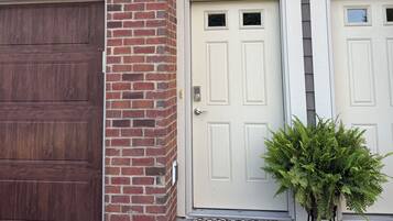 A residential building with a garage door, two numbered doors, and a small potted plant.