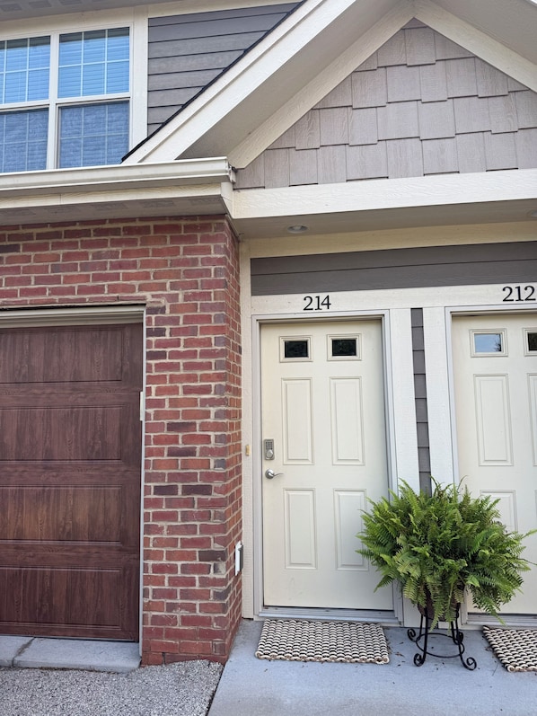 A residential building with a garage door, two numbered doors, and a small potted plant.